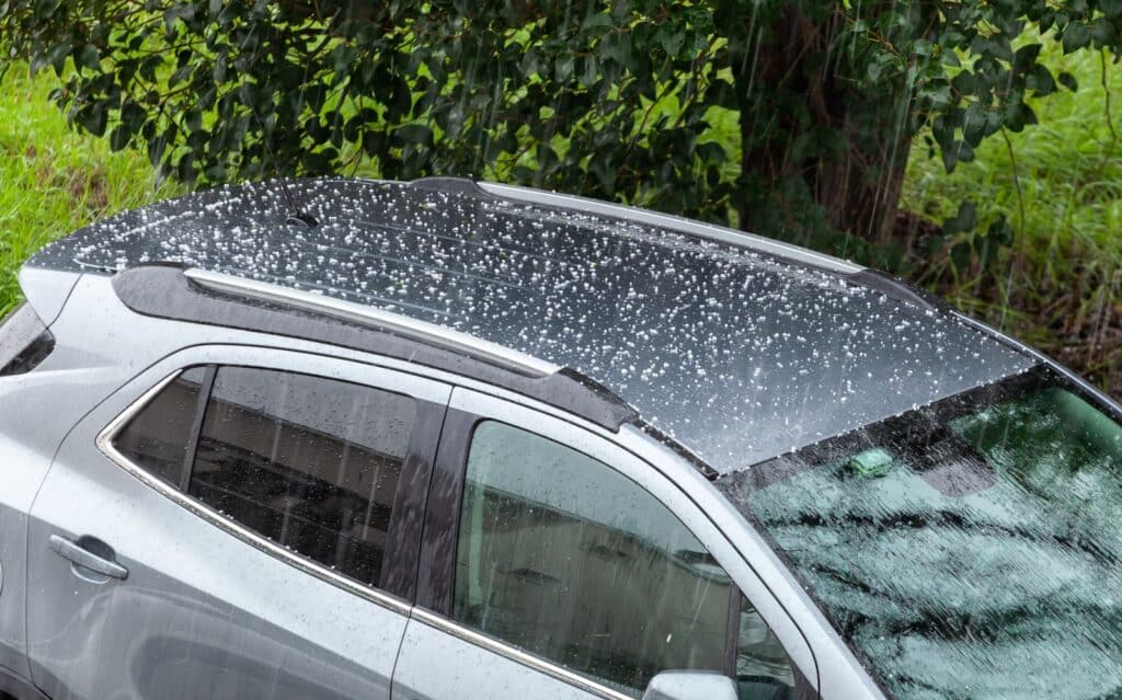 Hail falling over car roof. Hailstones can damage the bodywork