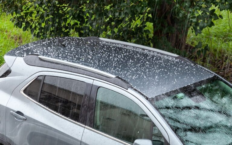 Hail falling over car roof. Hailstones can damage the bodywork