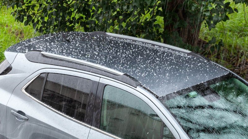 Hail falling over car roof. Hailstones can damage the bodywork